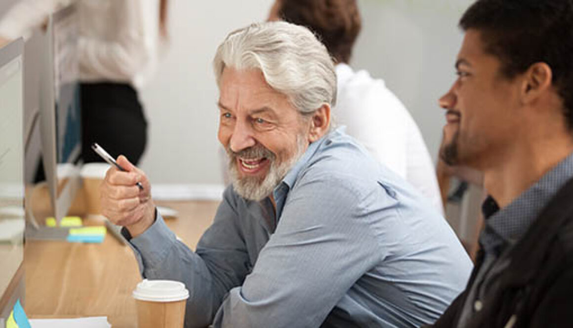 Smiling,Senior,Employee,Discussing,Email,With,African,Colleague,At,Workplace,